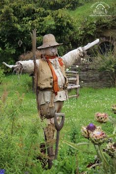 an old scarecrow is standing in the grass with his arms outstretched and legs spread out