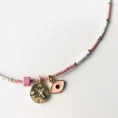 Pink and white miyuki beaded necklace with charms. Featuring a pink enamel evil eye charm, a Pink bead and a gold compass charm. Gold lobster clasp.  - Length 42cms - Bead size 6mm x 4mm - Evil eye charm 10mm x 6mm - Gold compass charm 10mm x 10mm I hope you enjoy my mini pieces of artwork and appreciate the work that goes into each creation.   Abacus Designs aims to be an eco friendly store and uses recycled packaging where possible. To view the full Abacus Designs range follow me instagram and Pink Heishi Beads Jewelry With Spacer Beads, Pink Adjustable Round Charm Necklace, Adjustable Pink Round Charm Necklace, Adjustable Pink Charm Necklace, Pink Bohemian Jewelry With Evil Eye Detail, Bohemian Pink Adjustable Charm Necklaces, Pink Bohemian Evil Eye Jewelry, Bohemian Pink Charm Necklace, Handmade Adjustable Pink Charm Necklaces