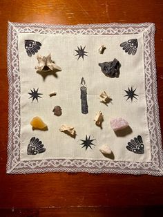 a table cloth with shells and other items on it sitting on top of a wooden table