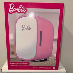 a pink and white box with barbie's logo on the front is sitting on top of a shelf