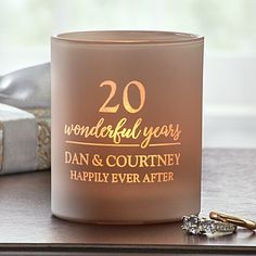 a candle that is sitting on a table next to some gold rings and a pair of earrings