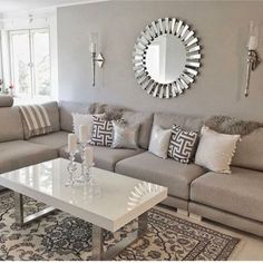 a living room filled with furniture and a large mirror on the wall above it's headboard