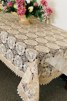 a vase with flowers on top of a table covered in lacy doily and lace