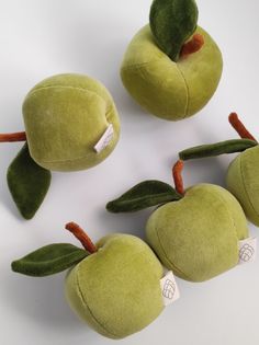 three green apples with leaves on them and one has a tag in the middle that says apple