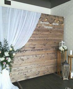 a wooden wall with white drapes and flowers on it