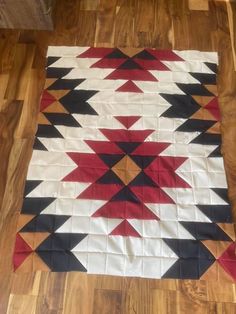 a red, black and white quilt is laying on the floor