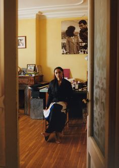 a man sitting in a chair next to a desk with a laptop computer on top of it