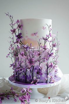 a three tiered cake with purple flowers on it