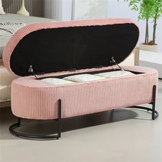 a pink ottoman with two white pillows and a black tray underneath it on the floor