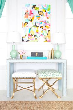 a desk with two stools and a painting on the wall