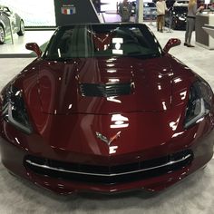 a red sports car is on display in a showroom with people looking at it