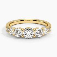 three stone diamond ring in yellow gold with diamonds on the band and side stones around the band