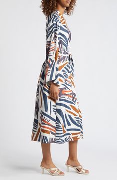 Dramatic kimono-inspired sleeves add bold movement to this fluid, flowy maxi dress that can also be worn as a topper and features an abstract geometric print. Each piece is designed for longevity. Every garment is made to order to reduce production waste. Surplice V-neck Long sleeves Tie belt 100% polyester Machine wash, line dry Made in Senegal Black Owned/Founded Spring Dresses With Abstract Print And Kimono Sleeves, Summer Dresses With Abstract Print And Kimono Sleeves, White Midi Dress With Abstract Print, Chic Flowy Midi Dress With Abstract Print, Flowy Abstract Print Maxi Dress, Flowy Maxi Dress With Abstract Print, Dramatic Sleeves, Wrap Maxi Dress, Flowy Maxi Dress