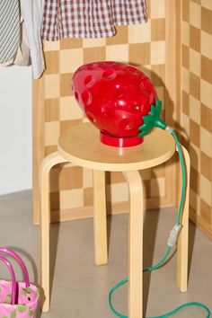 a red bowl sitting on top of a wooden table next to a pink purse and clothes