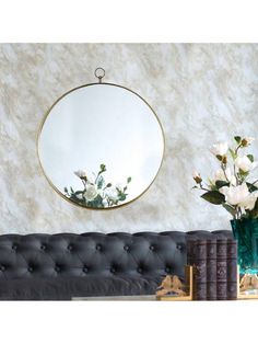 a living room with a couch, mirror and flowers on the table in front of it