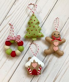 three christmas ornaments are hanging on a white wooden surface, one has a gingerbread house and the other is a tree