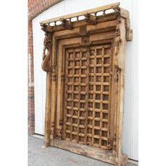 an old wooden door with intricate carvings on the front and sides, sitting against a white wall