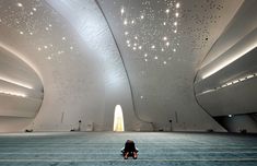 a person sitting on the floor in a large room with stars above and ceiling lights