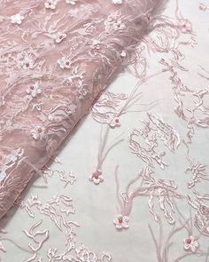 the fabric is pink and has white flowers on it, along with other material that looks like lace