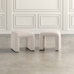 two white stools sitting on top of a cement floor