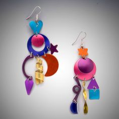 Aluminum Earrings - This fun pair of asymmetric earrings display charms in the shape of hearts, stars, crescent moons and other celestial shapes, hanging from a central galactic disk in shades of peacock blue, purple, orange, fuchsia, pink, yellow, and wine. The color penetrates the metal, and will not scratch or fade. Available with non-allergenic clip backs, ear wires, or post backs. Asymmetric Earrings, Earrings Display, Aluminum Earrings, Artful Home, Earring Display, Peacock Blue, Fuchsia Pink, Purple Orange, Diy Beads