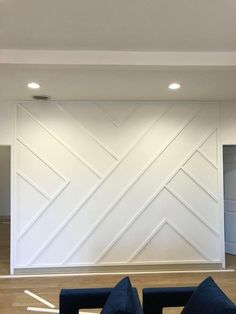 an empty room with two couches and a large white paneled wall in the background