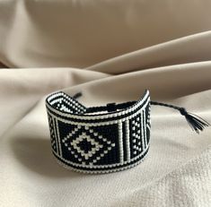 a black and white beaded bracelet sitting on top of a white cloth covered bed