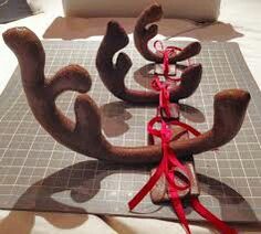 three reindeer antlers are tied up on a cutting board with red ribbon around them