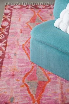 a blue couch sitting on top of a pink rug next to a white stuffed animal