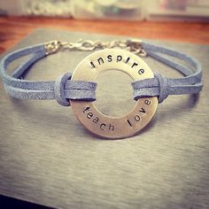 a bracelet with the words inspire, teach and love on it sitting on top of a table