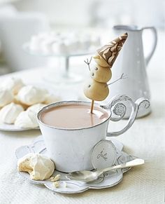 a cup of coffee with marshmallows on the side and a spoon in it