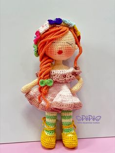 a crocheted doll with long red hair wearing yellow boots and a pink dress