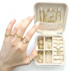 a woman's hand holding an open jewelry box with rings and bracelets in it