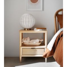 a white lamp sitting on top of a wooden table next to a bed with pillows