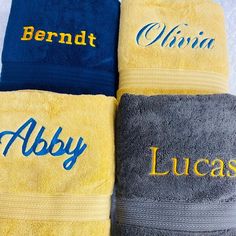 three personalized towels are lined up on a toweling sheet, one is blue and the other is yellow