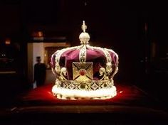 a crown sitting on top of a red velvet covered bench in a dark room,