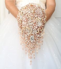 a woman in a wedding dress holding a bridal gown with pearls and beads on it