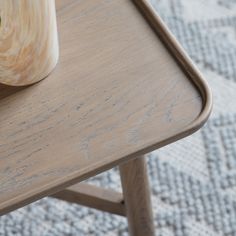 a vase sitting on top of a wooden table next to a plant in a pot