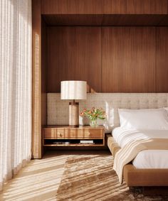 a bed sitting in a bedroom next to a wooden dresser and window with white curtains