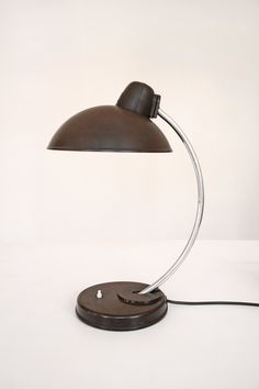 a lamp that is sitting on top of a table next to a white wall and floor