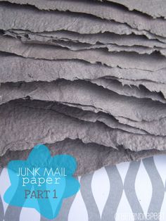 a pile of grey paper sitting on top of a white and blue table cloth with the words junk mail paper part 1