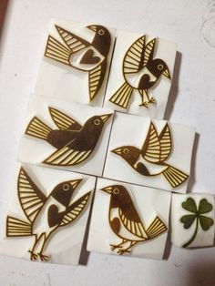 four birds sitting on top of white tiles with gold trimmings and shamrock leaves