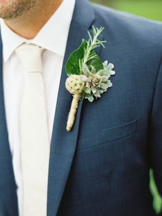 a man wearing a suit and tie with a boutonniere on his lapel