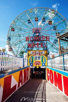 an amusement park with a ferris wheel in the center and people walking around it on either side