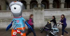 an inflatable character is walking down the street with two women and a baby stroller