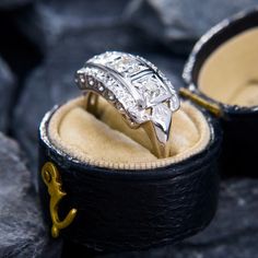 an engagement ring is sitting in a box on some rocks with the lid open to show it's inside