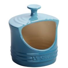 a blue ceramic dog house with the door open and it's lid opened to reveal a brown substance inside