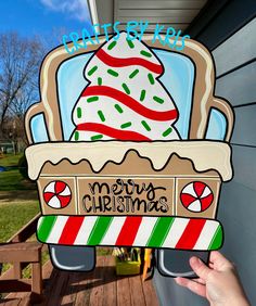 a hand holding up a cardboard cutout of a merry christmas ice cream sundae