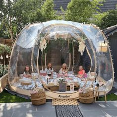 a group of people sitting at a table in a bubble house with an awning