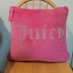 a pink pillow with the word juicy on it sitting on a wooden chair next to a wall